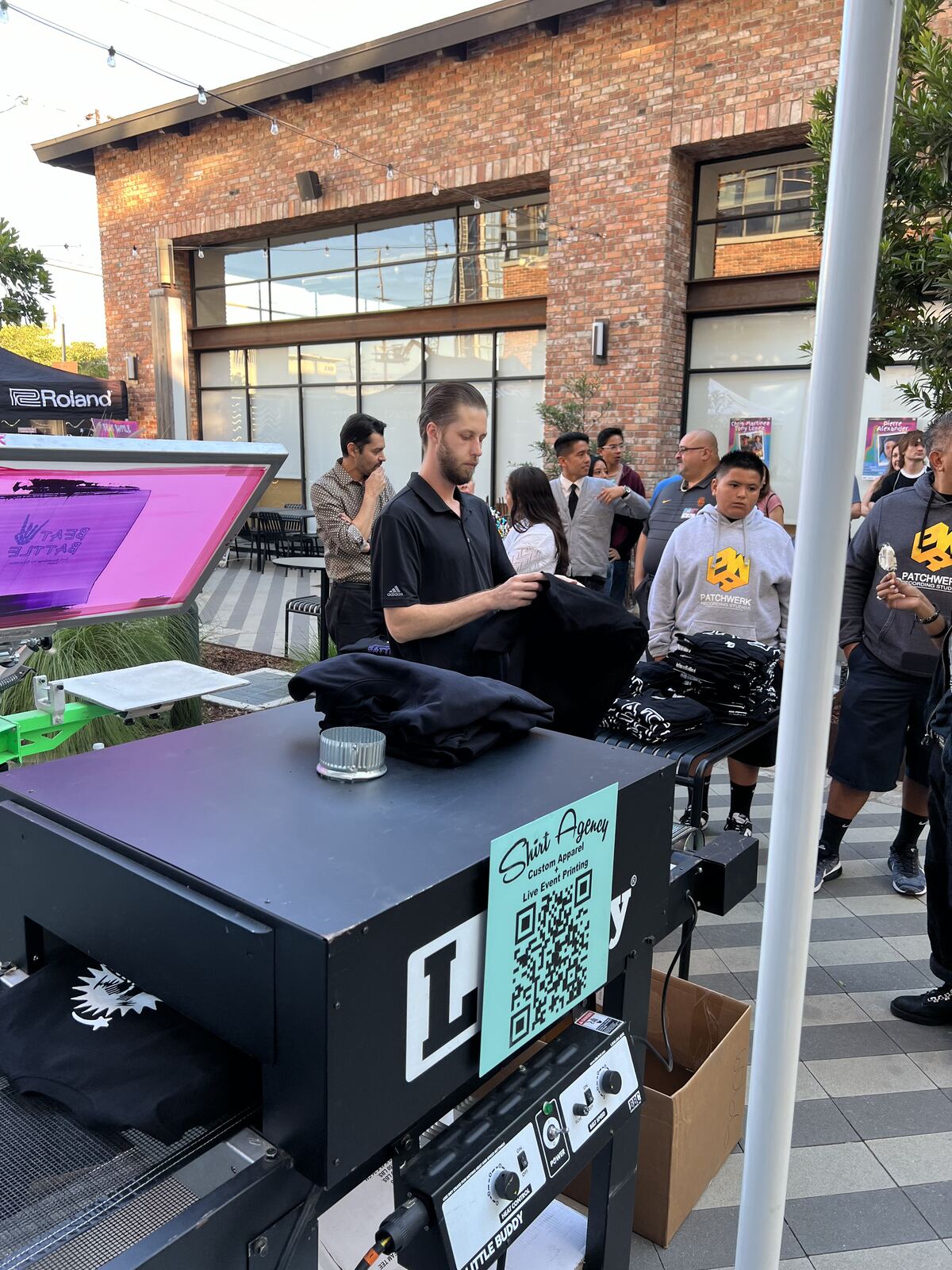 Street-level event booth with a live printing setup and visitors in an urban venue